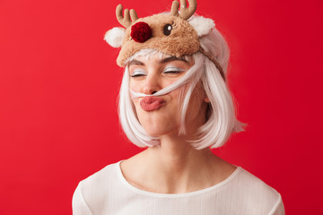 Funny woman dressed in carnival christmas costume posing isolated over red wall background having fun.