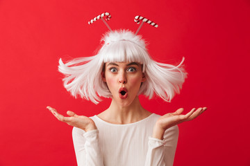 Excited young shocked woman dressed in carnival christmas costume posing isolated over red wall background.
