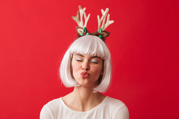 Young happy woman dressed in carnival christmas costume posing isolated over red wall background.