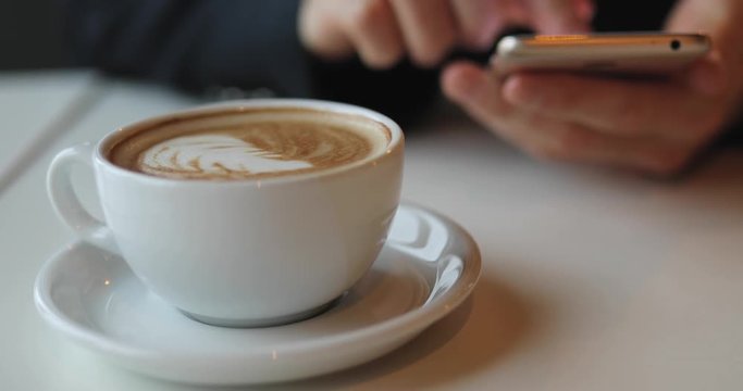 Businessman is working with a mobile phone in coffe shop and drinking coffe