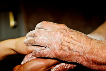 Hands of an old grandmother in the hands of the young daughter of a close-up