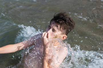 Teen boy closing his nose dives in the wave of sea in the tropical resorts. Concept of summer vacation