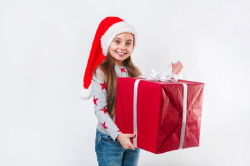 Smiling funny child in Santa red hat holding Christmas gift in hand. Christmas concept.