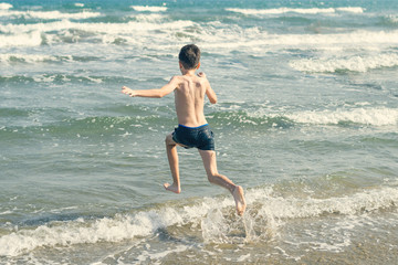 Boy Jumping In Sea Waves with Water Splashes. Concept of summer vacation