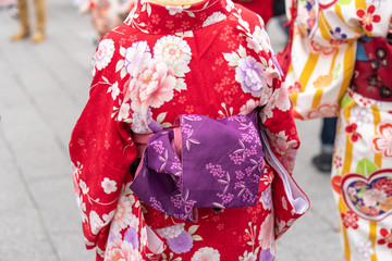 Naklejka premium Young girl wearing Japanese kimono standing in front of Sensoji Temple in Tokyo, Japan. Kimono is a Japanese traditional garment. The word 