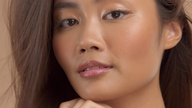 closeup thai asian model with ideal glowing strobing skin turning and watching aside and to the camera