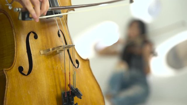 Closeup of a playing the cello in the background playing the violin