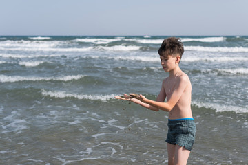 Fototapeta na wymiar Cheerful boy teenager shows his hands in the healing healing mud from the sea