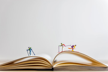 Miniature skiers sliding down the open book