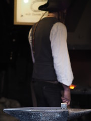 Blacksmith working metal with hammer in the forge for good luck on a christmas market in Cologne.