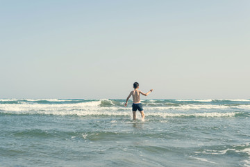 Boy Jumping In Sea Waves with Water Splashes. Concept of summer vacation