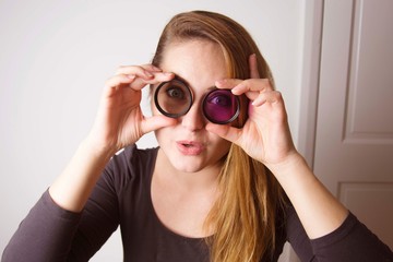 Young woman looking through camera lens and smile. Photography tools and equipment.