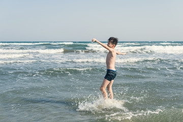 Fototapeta premium Boy Jumping In Sea Waves with Water Splashes. Concept of summer vacation