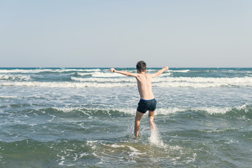 Boy Jumping In Sea Waves with Water Splashes. Concept of summer vacation