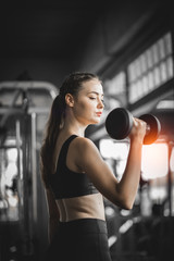Fototapeta na wymiar Fit beautiful young woman caucasian posing at the camera in sportswear. Young woman holding dumbbell during an exercise class in a gym. Healthy sports lifestyle, Fitness concept.