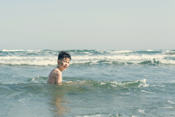 Fototapeta premium Boy Jumping In Sea Waves with Water Splashes. Concept of summer vacation
