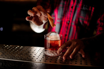 Bartender adding to a Boulevardier cocktail orange zest
