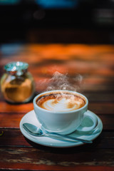 Hot coffee latte cappuccino spiral foam on wooden table in coffee shop cafe with vintage color tone filter background. With copy space for your text. Color tone effect