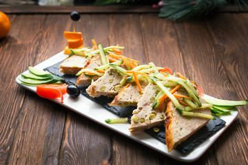 Christmas dinner. Grilled stuffed and sliced chicken fillets with vegetables on a slate shale plate