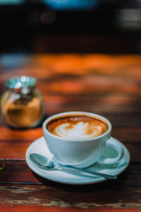 Hot coffee latte cappuccino spiral foam on wooden table in coffee shop cafe with vintage color tone filter background. With copy space for your text. Color tone effect