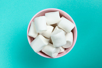 marshmallow laid out on blue paper background. pastel creative textured pattern.