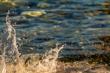 Splash of sea water. Clear sea, the play of light in the droplets. Glare and blurred background.