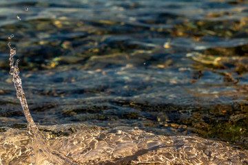 Splash of sea water. Clear sea, the play of light in the droplets. Glare and blurred background.