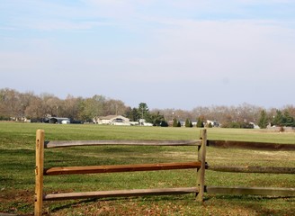 A view of the countryside landscape behind a wood fence.