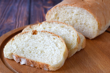 Fresh homemade bread sliced on wooden background.