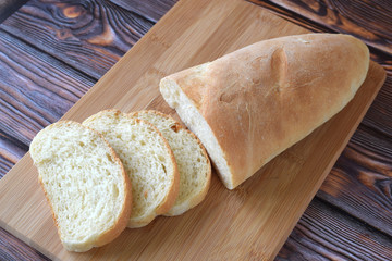 Fresh homemade bread sliced on wooden background.