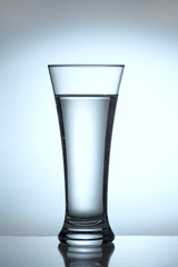 Transparent glass with water, lights at the back, close-up