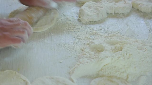 Woman rolling out dough on a cutting board. 