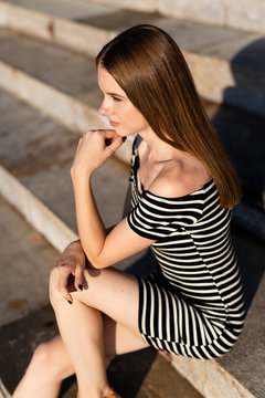 Young woman sitting on stairs at sunset
