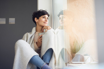 Relaxed woman at home sitting at the window