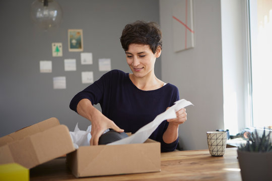 Smiling woman packing parcel at home