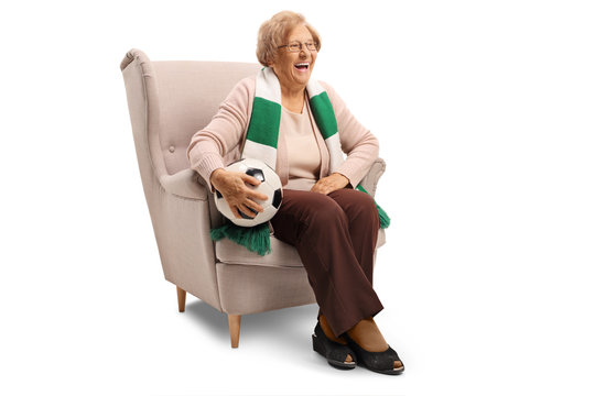 Happy senior woman sitting in an armchair with a soccer ball and a scarf