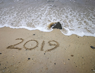 Year 2019 written on beach sand background
