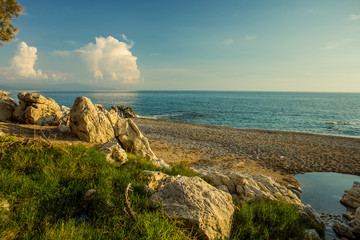 Fototapeta na wymiar beautiful tropic exotic south Mediterranean landscape sea shore line beach with rocks and stone along waterfront in vivid colors from evening sun light before sunset