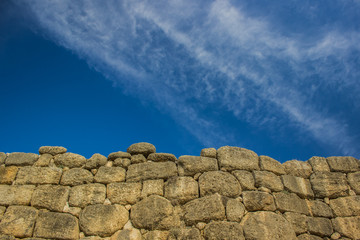 ancient old stone brick wall texture on blue sky empty background horizontal wallpaper concept with copy space