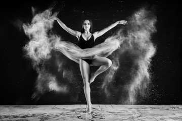 beautiful slender girl with long hair dancing in a dark Studio in a cloud of dust