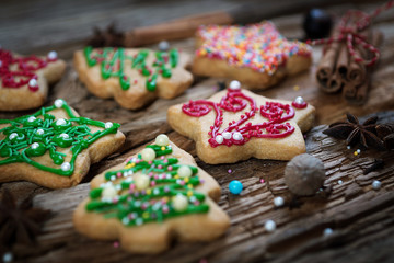 gingerbread in the form of Christmas trees, stars and red-green on a wooden background with cinnamon and star anise