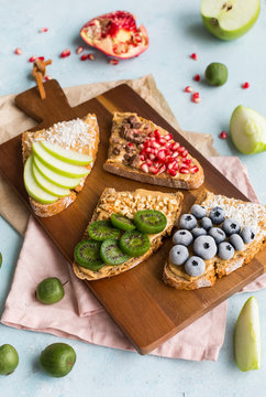Bread slices with various toppings on wooden board