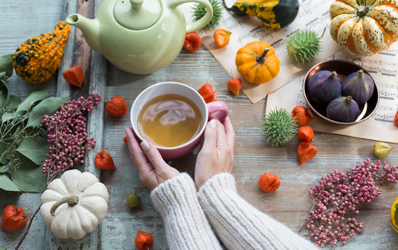 Woman warming her hands on cup of tea in autumn