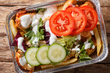 Recipe Dutch fast food kapsalon of french fries, chicken, fresh salad, cheese and sauce close-up. Horizontal top view