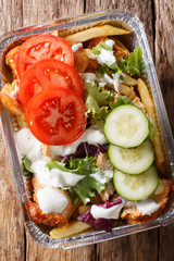 Recipe Dutch fast food kapsalon of french fries, chicken, fresh salad, cheese and sauce close-up....