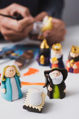 man painting figurines of a nativity scene
