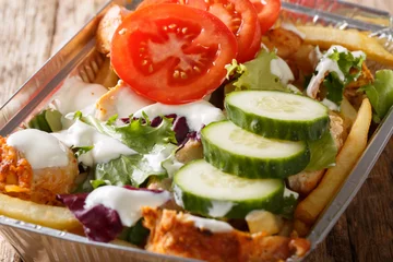 Foto op Plexiglas Traditionele Nederlandse fastfood kapsalon van frietjes, kip, verse salade en saus close-up. Horizontaal © FomaA