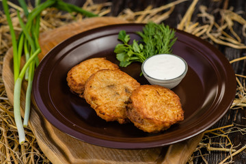 pancakes with sour cream and parsley on a clay plate