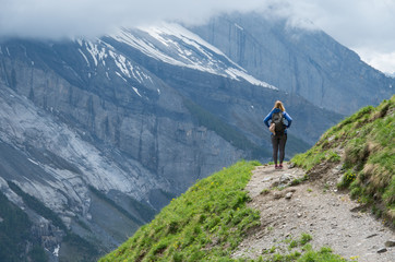 Young beautiful woman standing on a mountain path looking out over the range