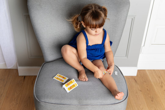 Little girl putting plaster on leg